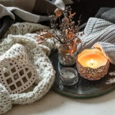 A candle, blankets and jar of dried flowers