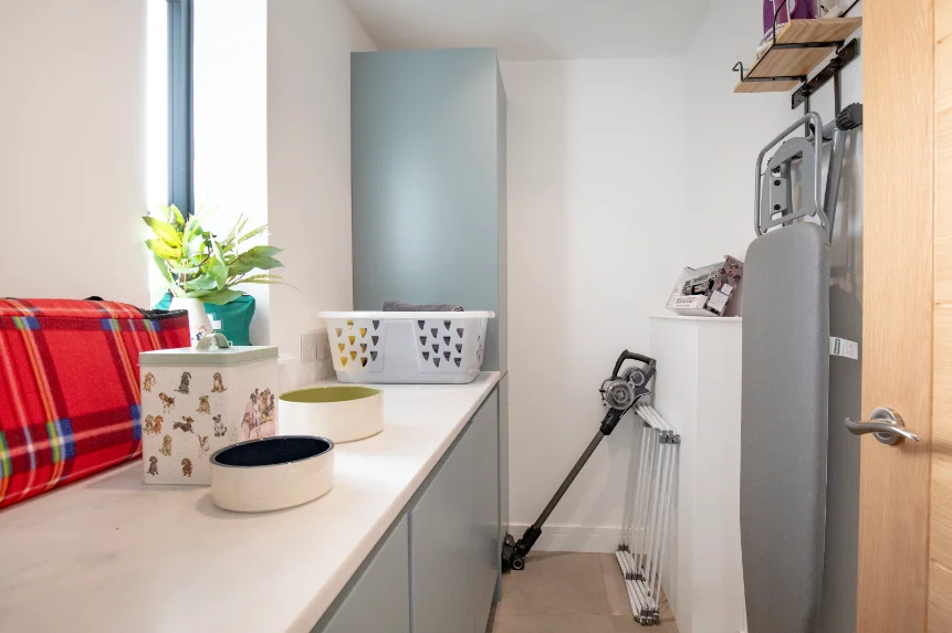 Modern utility room with ironing board, vacuum cleaner, laundry basket and clothes airer.