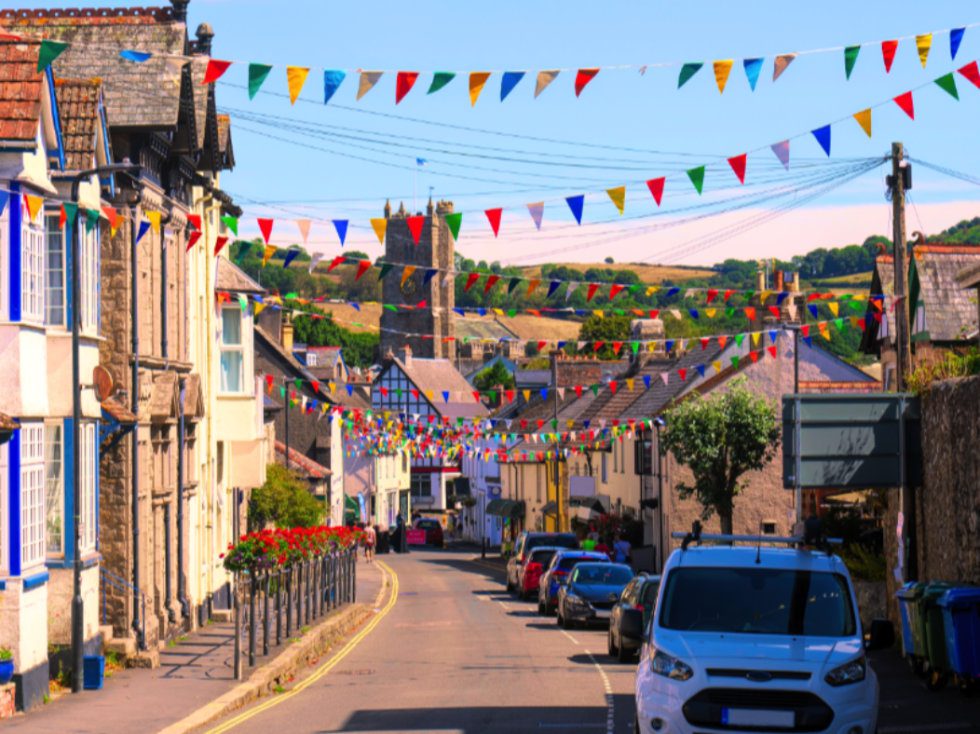 Colourful bunting across a road leading down to the church in the town of Beer in Devon