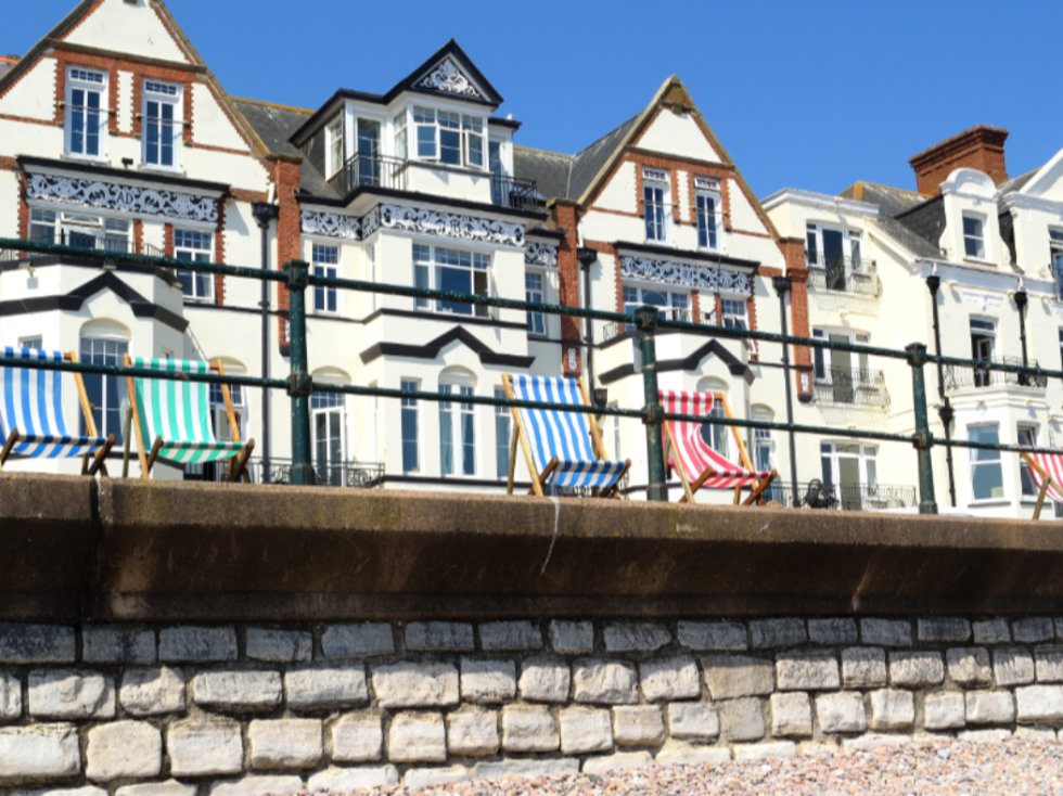 Multi-coloured deckchairs in front of a parade of houses on the seafront at Sidmouth in Devon